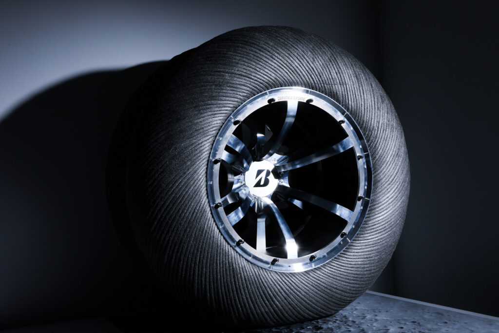 暗い部屋の中に月面探査車用タイヤのコンセプトモデルが月の明かりのようなライトアップがされている写真