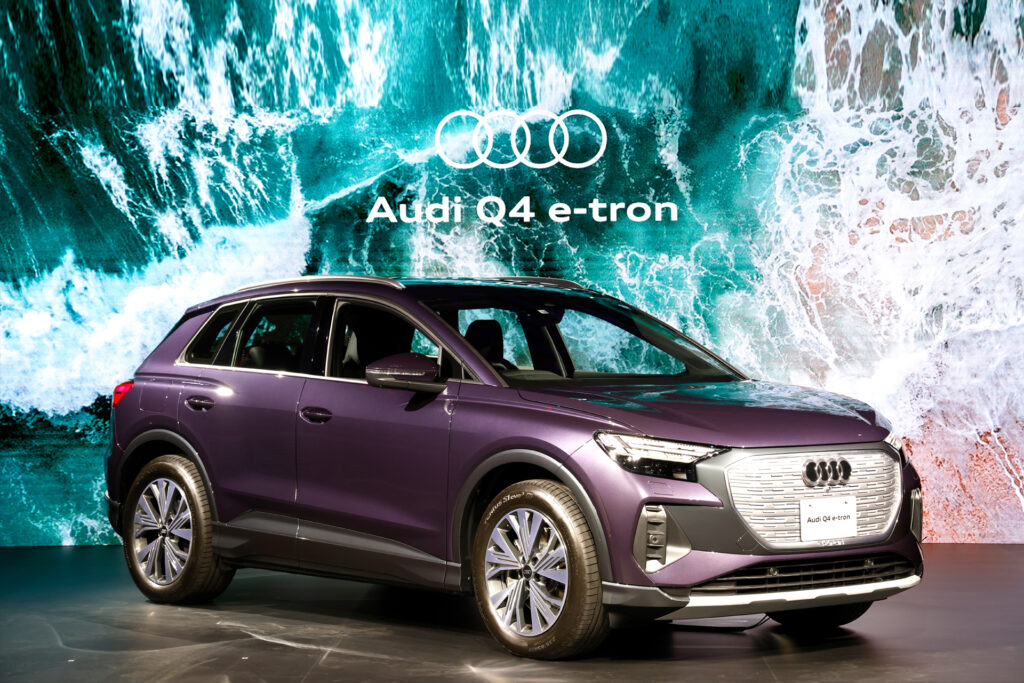 イベントで披露される紫色のAudi Q4 e-tronの写真。クルマの背景には海の波の映像が流れている。