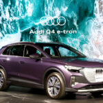 イベントで披露される紫色のAudi Q4 e-tronの写真。クルマの背景には海の波の映像が流れている。