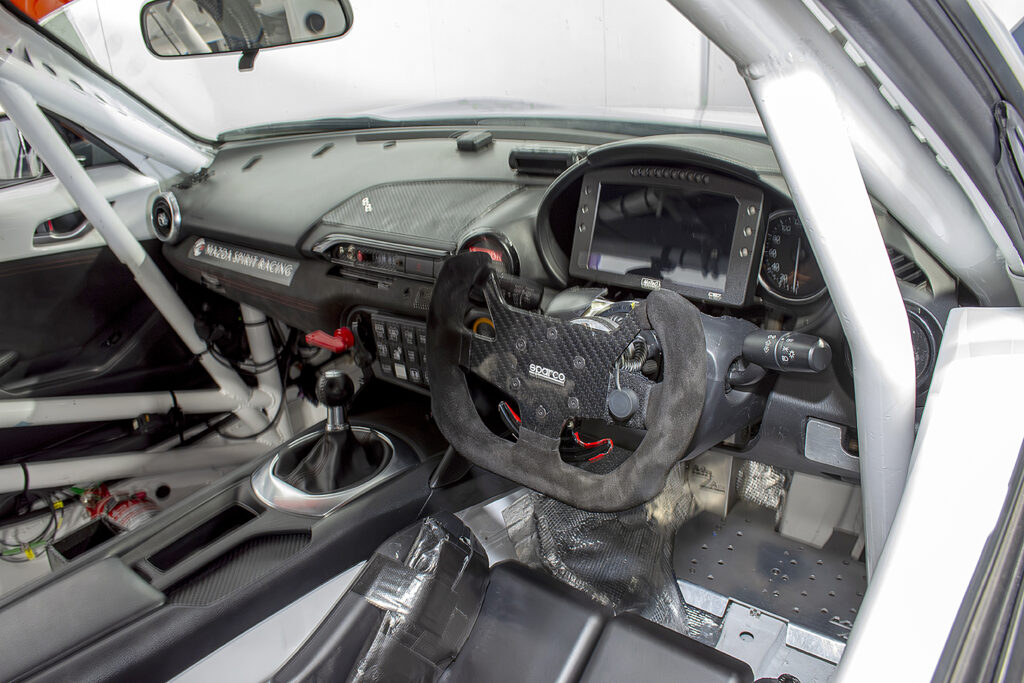レーシングカー12号車のコックピット。ステアリングはレーシンググローブの着用時に抜群のグリップを約束するスウェードタイプを採用